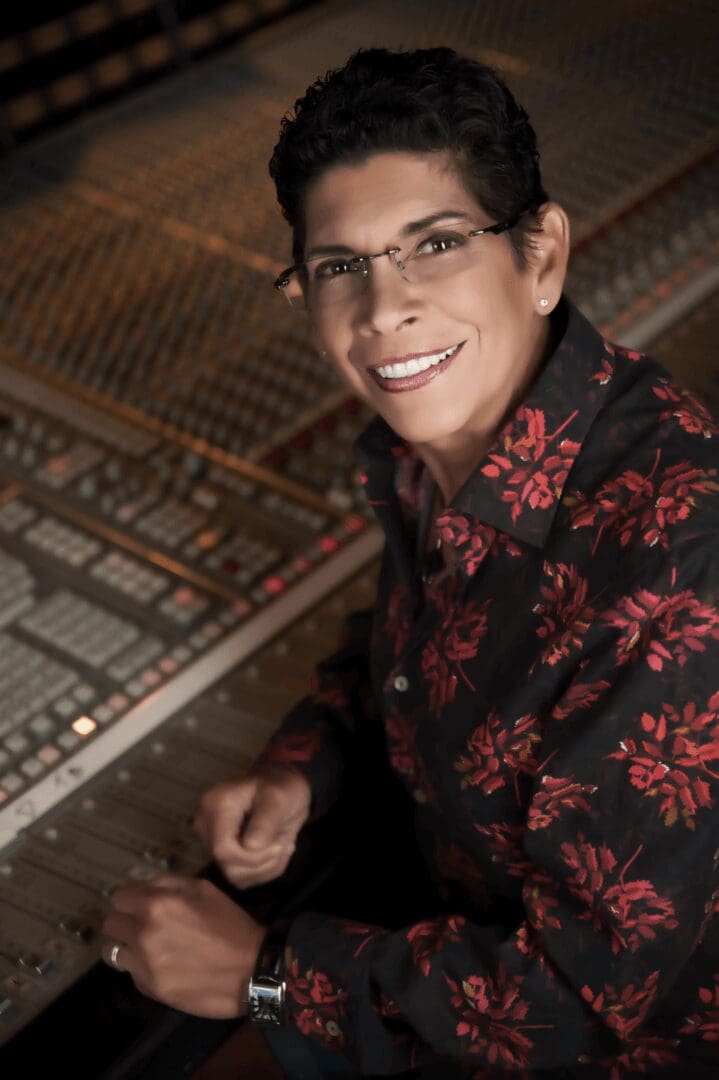 A man sitting in front of a sound board.