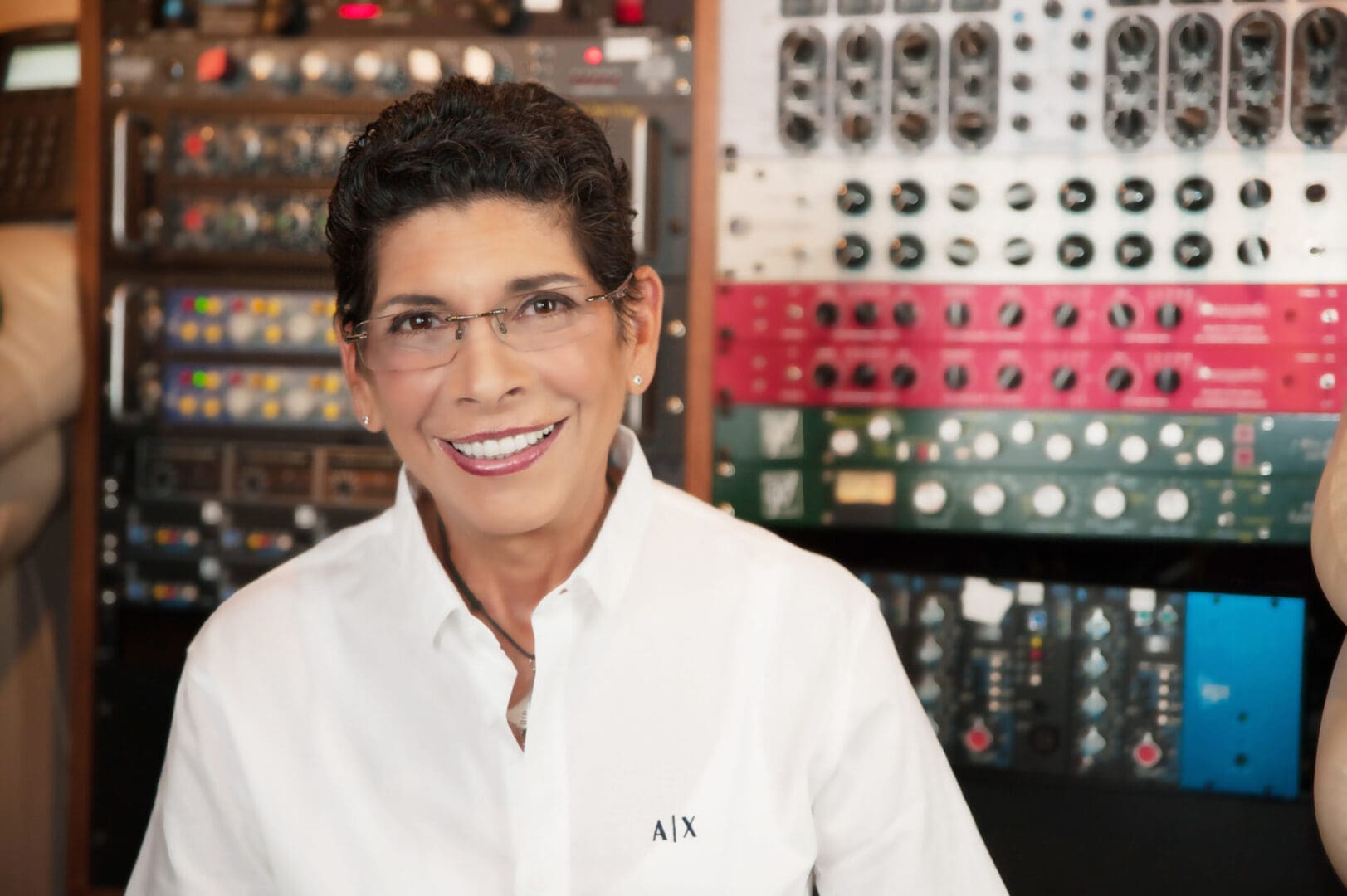 A woman in glasses and white shirt smiling.